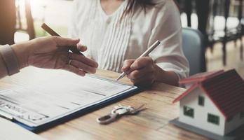 o corretor de imóveis está explicando o estilo da casa aos clientes que entram em contato para ver o projeto da casa e o contrato de compra, a aprovação do empréstimo hipotecário e o conceito de seguro. foto