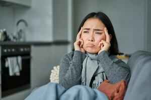 doente coreano mulher tosse e sentindo-me indisposto, fazendo careta, tem gripe, tossir frio ou gripe, ficando às casa foto