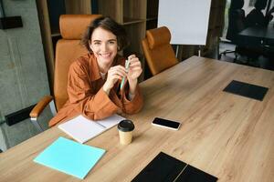 retrato do trabalhando mulher sentado dentro escritório, vestindo casual, informal roupas, bebendo café e lendo documentos, fazer notas foto