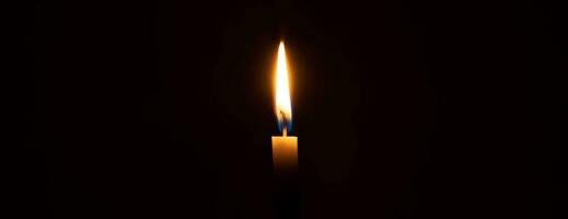 uma única chama de vela acesa ou luz brilhando em uma vela laranja em fundo preto ou escuro na mesa na igreja para o natal, funeral ou serviço memorial com espaço de cópia foto