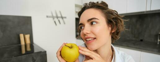 fechar acima retrato do saudável, lindo jovem mulher segurando a maçã, sorridente foto