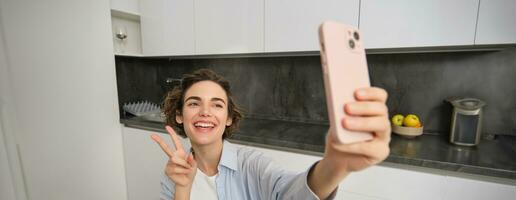feliz, lindo morena menina leva selfie às lar, poses para foto com Smartphone