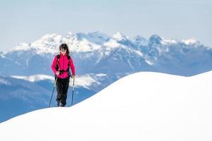 jovem no cume de tanta neve sobe em direção ao topo nas montanhas foto