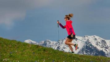 caminhada nórdica e trilha correndo uma garota com gravetos em uma montanha dourada com fundo de neve foto
