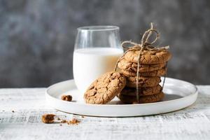 biscoitos de aveia e um copo de leite em um prato branco foto