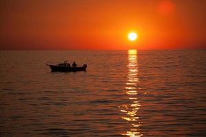 pescador em um barco durante o pôr do sol