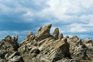 afiado irregular basalto pedras em a mar costa, capa estúpido em kunashir ilha foto