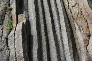 superfície do uma Rocha parede formado de colunar basalto foto