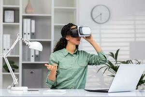 bem sucedido latim americano mulher dentro escritório usando vr óculos para vídeo ligar e conversando conectados dentro virtual realidade simulador, conectados conferência com colegas controlo remoto dentro metaverso. foto