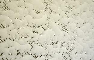 malha de metal de close-up coberta com uma espessa camada de neve nas células foto