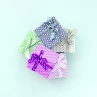 pilha de pequenas caixas de presente coloridas com fitas encontra-se em um fundo violeta. vista superior plana do minimalismo foto