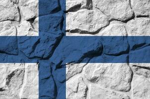 Finlândia bandeira retratado dentro pintura cores em velho pedra parede fechar-se. texturizado bandeira em Rocha parede fundo foto