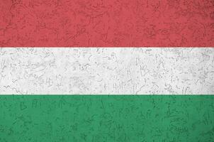 bandeira da Hungria retratada em cores brilhantes de tinta na parede de reboco em relevo antigo. banner texturizado em fundo áspero foto