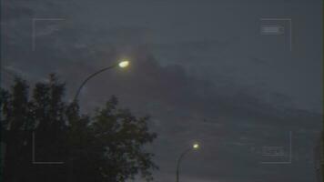 Visão através a vídeo Câmera para a cinzento nublado céu tarde céu e rua luzes às a cidade rua. imagens de vídeo. vídeo tiroteio foto