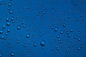 água gotas em Sombrio azul fundo foto