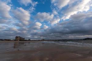 o céu está coberto de nuvens escuras e a praia está nublada foto