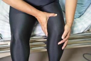 paciente mulher asiática de meia-idade tocar e sentir dor no joelho, conceito médico saudável. foto