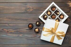 branco caixa com chocolates doces e dourado fita. topo Visão com cópia de espaço foto