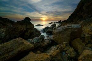 pôr do sol sobre a mar com pedras às chanthaburi, Tailândia foto