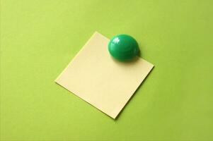 amarelo adesivo com em branco espaço para inscrição ou lembrete em uma verde fundo, em anexo para uma verde volta magnético. foto