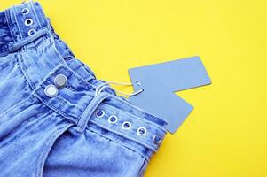 plano deitar, detalhe do jeans jeans com em branco cinzento rótulo em amarelo fundo. foto