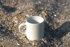 branco caneca café em a areia. foto