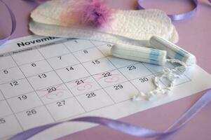 menstrual almofadas e absorvente interno em menstruação período calendário com em lilás fundo. foto