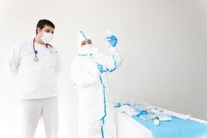 médico com máscara e traje de proteção usando conta-gotas no hospital foto
