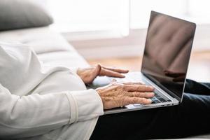 mulher idosa calma navegando no laptop na sala de estar foto