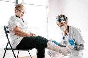 enfermeira enfaixando perna do paciente