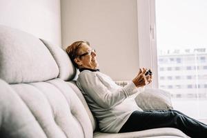 mulher idosa com conteúdo com console jogando videogame foto