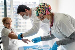 médicos colhendo amostra de sangue de paciente idoso foto