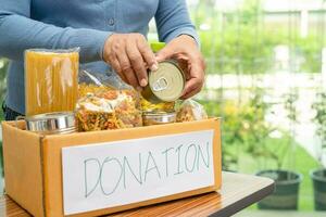 voluntários colocando vários alimentos secos na caixa de doação para ajudar as pessoas. foto