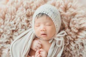 bebê recém-nascido asiático dormindo com chapéu de malha foto