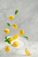 voando macaroons de cítrico amarelo com folhas de hortelã sobre o prato branco sobre fundo de concreto. copie o espaço foto