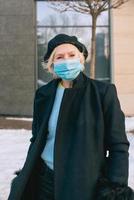 mulher elegante sênior na boina e elegante casaco preto e máscara médica, caminhar ao ar livre. bloqueio, pandemia, conceito de proteção