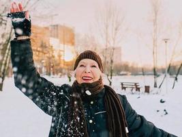 mulher sênior com chapéu e jaqueta esportiva bola de neve no parque de inverno de neve. inverno, idade, esporte, atividade, conceito de temporada foto
