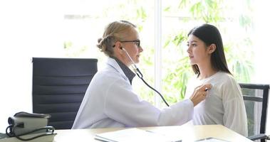 médico usando estetoscópio para examinar o paciente em seu consultório em hospitais foto