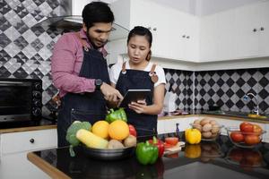 casal jovem feliz e sorridente cozinhando comida na cozinha de casa foto