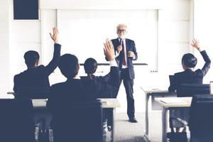 audiência de negócios levantando a mão enquanto empresário está falando em treinamento para opinião com o líder da reunião na sala de conferências
