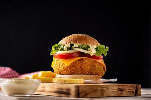 hambúrguer de frango crocante com queijo e batata frita foto