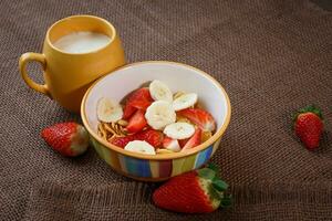 saudável café da manhã. flocos de milho, fresco morangos, banana e leite foto