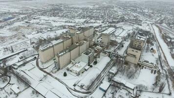 grão terminal dentro a inverno temporada. coberto de neve grão elevador dentro rural áreas. uma construção para secagem e armazenando grão. foto