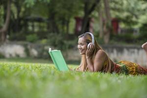mulher asiática, ouvindo música favorita em fones de ouvido e lendo um livro. tempo feliz e relaxe. foto