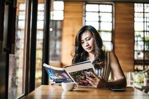linda mulher lendo revista no café foto