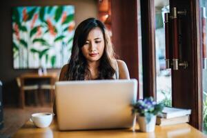 linda mulher trabalhando com um laptop em uma cafeteria foto