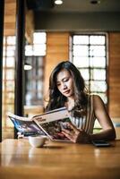 linda mulher lendo revista no café foto