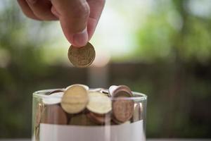 mão colocando moedas na jarra com a etapa da pilha de dinheiro crescendo e economizando dinheiro foto