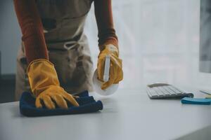 escritório limpeza serviço. zelador pulverização escrivaninha. local de trabalho higiene foto