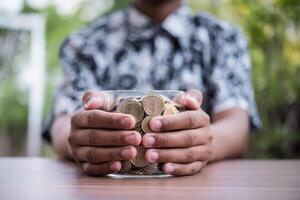 mão colocando moedas na jarra com a etapa da pilha de dinheiro crescendo e economizando dinheiro foto